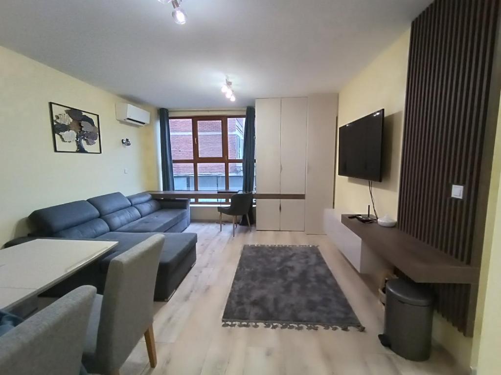 a living room with a blue couch and a table at Apartament Tzar Kaloyan in Burgas
