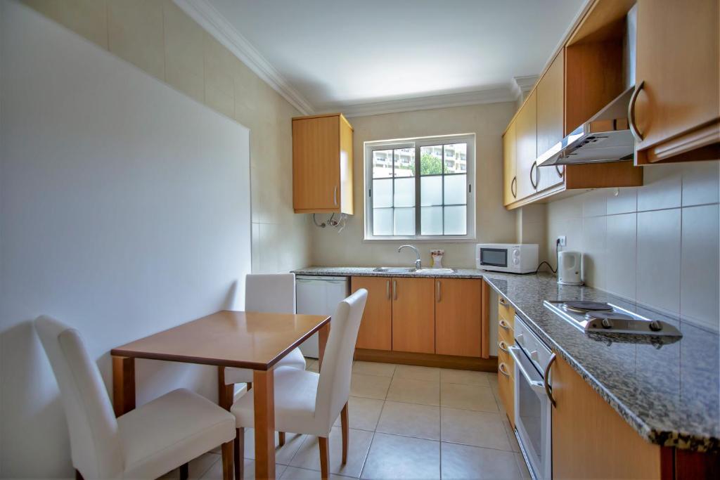 a small kitchen with a table and chairs and a sink at Aquamar Albufeira Aparthotel in Albufeira