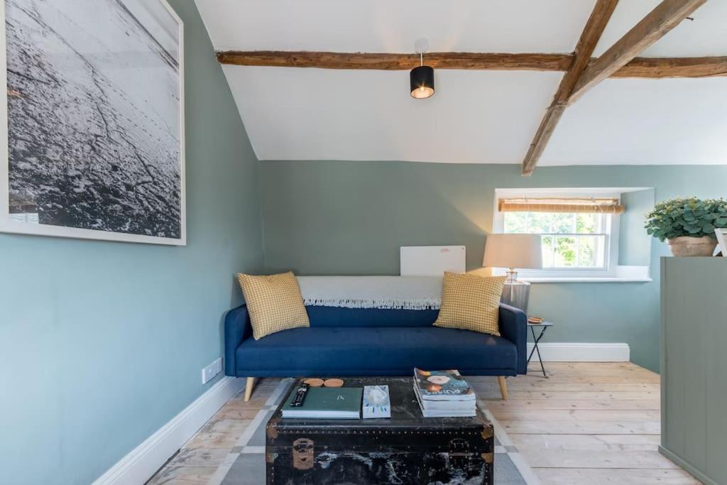 a living room with a blue couch and a table at Talliers Cottage - Characterful & Central in Cirencester