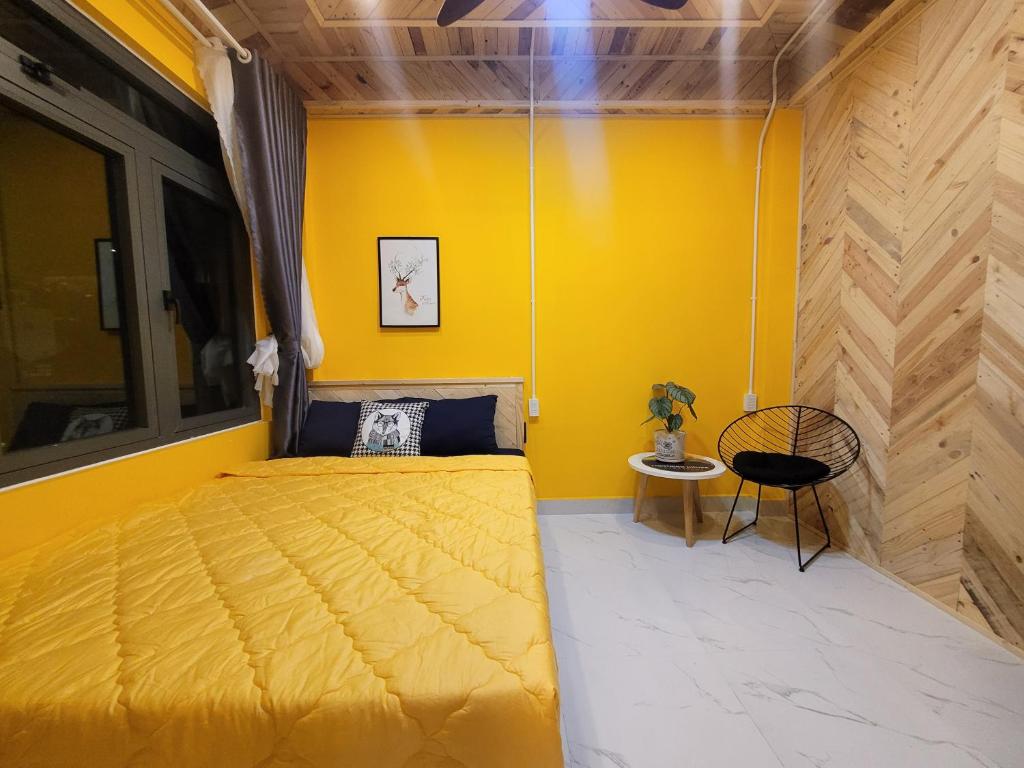 um quarto amarelo com uma cama e uma cadeira em Lightning House em Da Lat