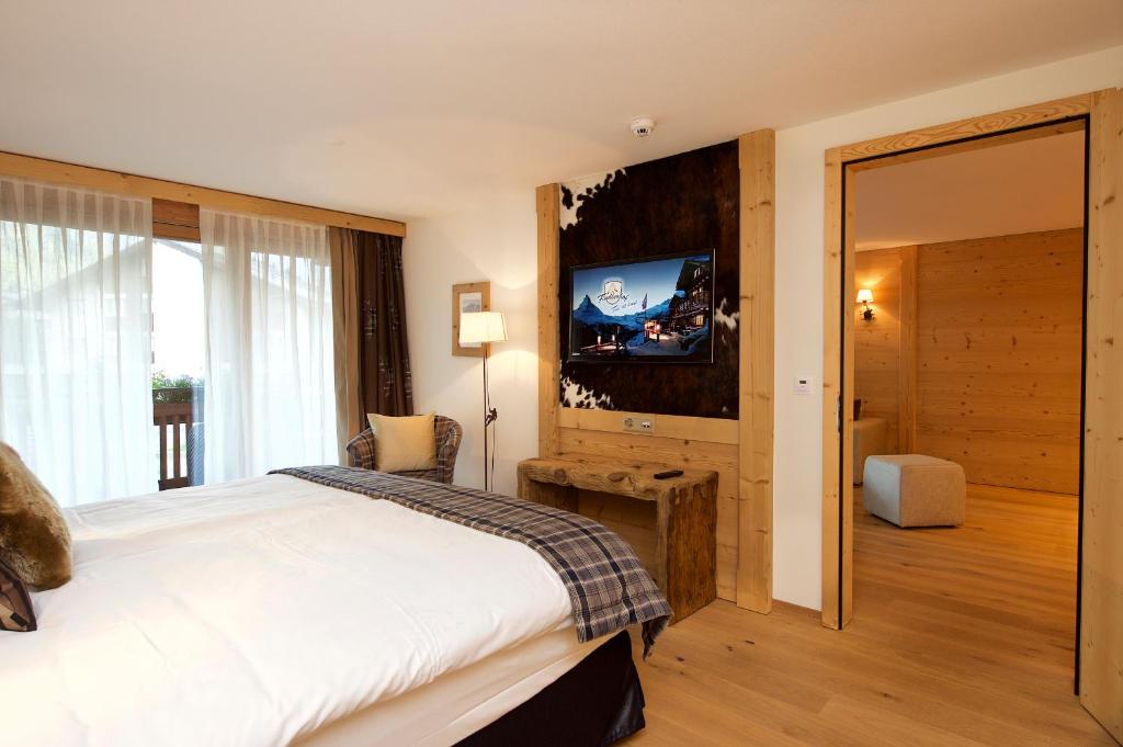 a bedroom with a bed and a flat screen tv at Matterhorn Lodge Boutique Hotel & Apartments in Zermatt