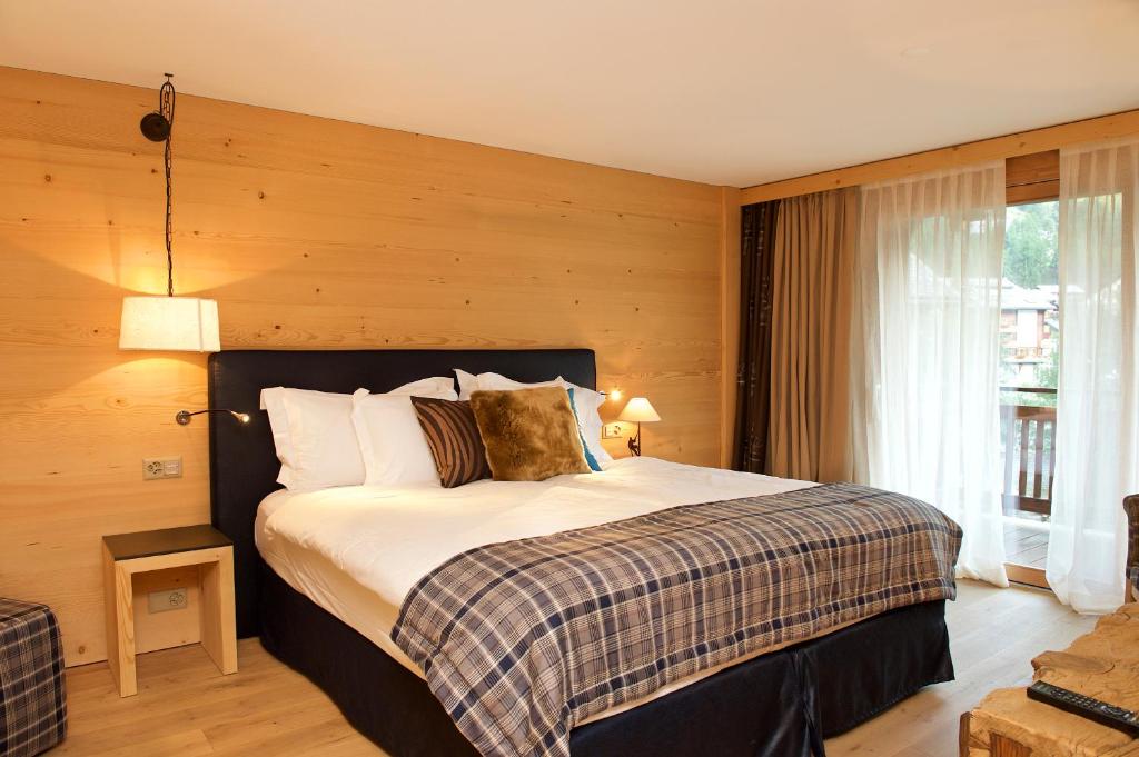 a bedroom with a large bed with wooden walls at Matterhorn Lodge Boutique Hotel & Apartments in Zermatt