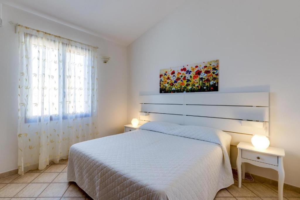 een slaapkamer met een wit bed en een schilderij aan de muur bij La Casa delle Zie - Cabras in Càbras