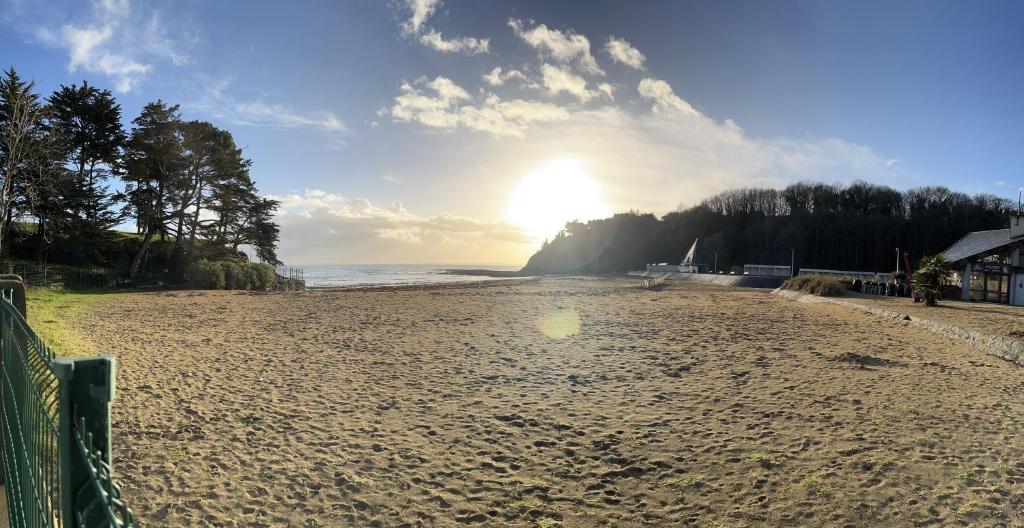 a sandy beach with the sun in the distance at * Le Hameau de la plage * in Étables-sur-Mer