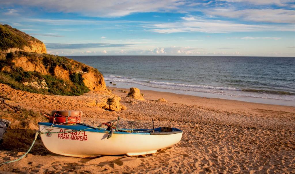 a boat sitting on a sandy beach next to the ocean at Aquamar Albufeira Aparthotel in Albufeira