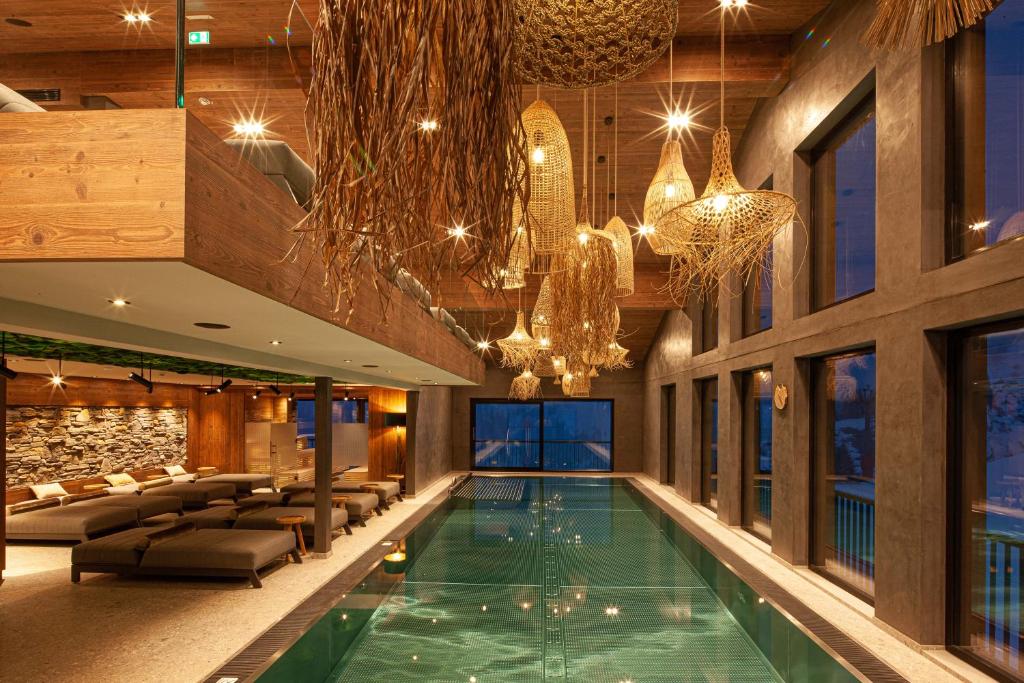 a swimming pool in a hotel with chandeliers at Hotel Walisgaden superior in Damuls