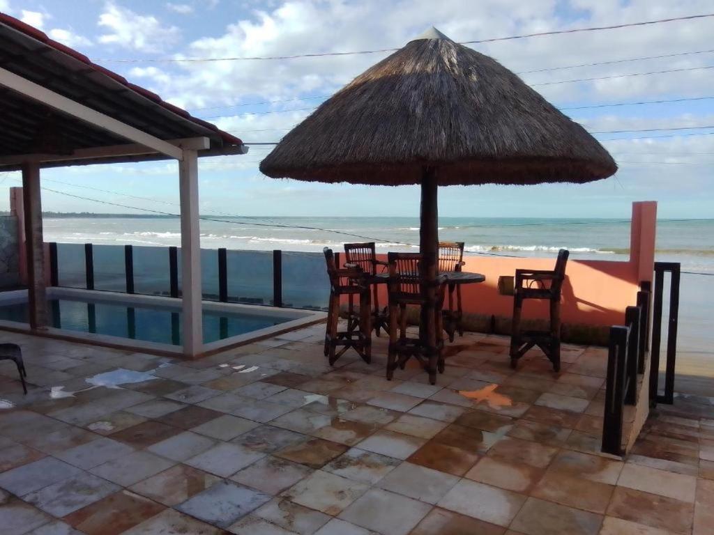 uma mesa com cadeiras e um guarda-sol na praia em B&B Beach House Pousada Exclusiva pés na água Pontal do Peba única em Alagoas em Pontal do Peba