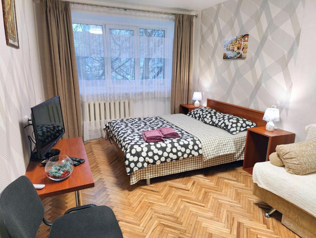 a bedroom with a bed and a table and a tv at Bright and cozy apartments in the center in Vinnytsya