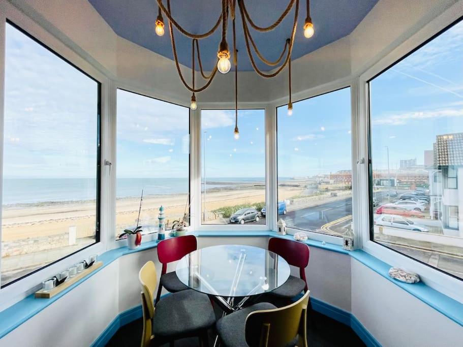 a room with a table and chairs in front of windows at The Sea Deck Apartment - Westbrook Bay Beach - By Goldex Coastal Breaks in Kent