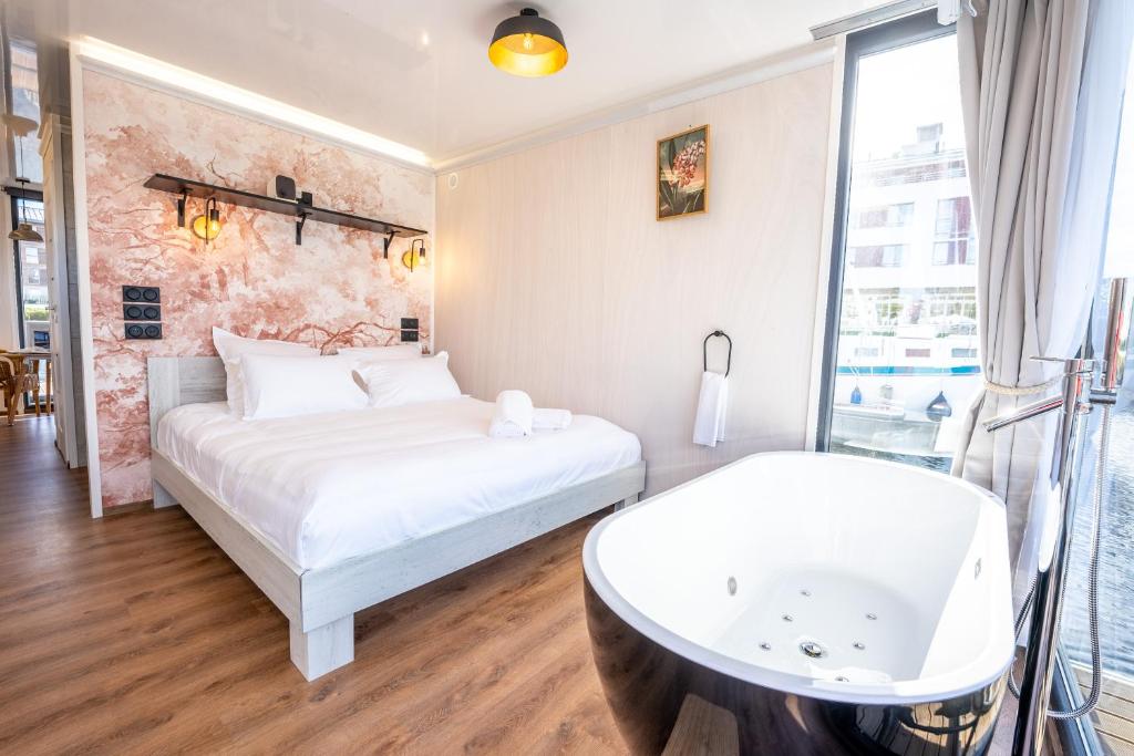 a bedroom with a white bed and a bath tub at L&#39;Escale Royale L&#39;Isle Adam à 20 minutes de Paris CDG in LʼIsle-Adam