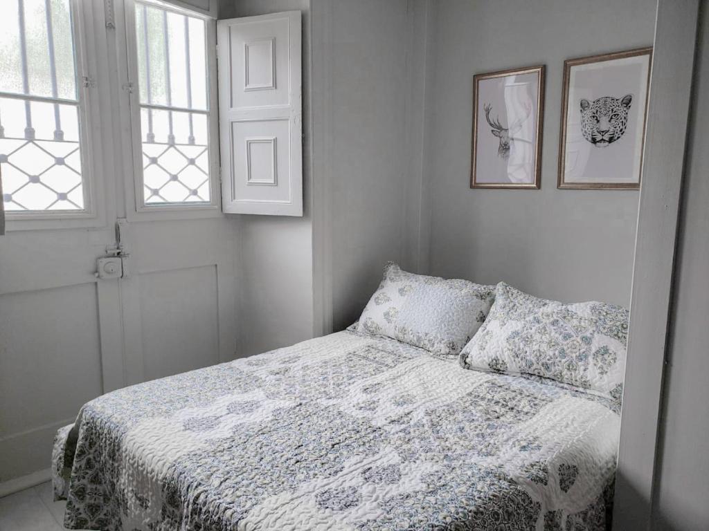 a bedroom with a bed with a blanket and two windows at Casa Hostal Paso por La Serena in La Serena