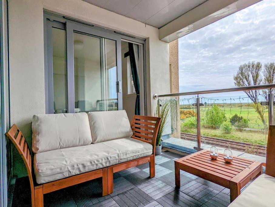 sala de estar con sofá y mesa en el balcón en Beautiful 2 bedroom flat overlooking golf course en Carnoustie