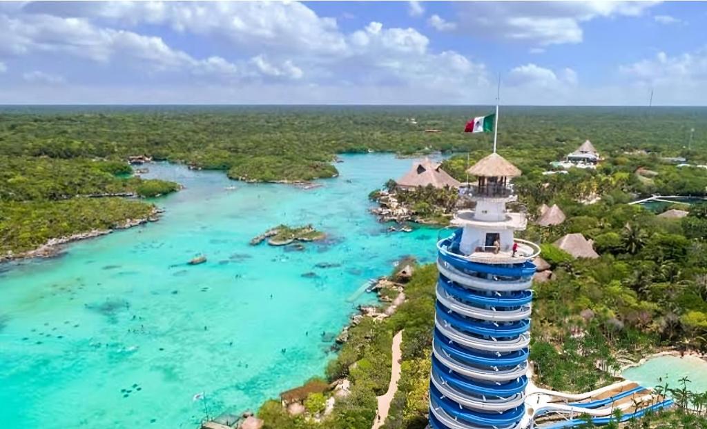 un faro con una bandera sobre un cuerpo de agua en La Casa de Leo Recamara 1 Villa Cardiell QROO en Playa del Carmen