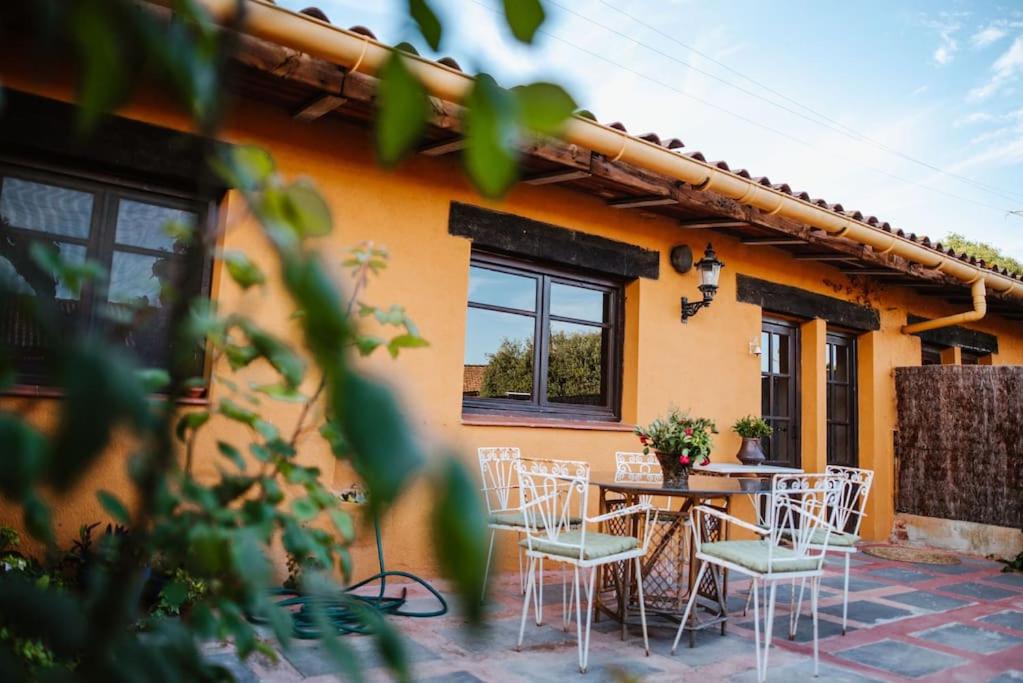 um pátio com uma mesa e cadeiras em frente a uma casa em La BERBENA casa rural en el campo em Tordera