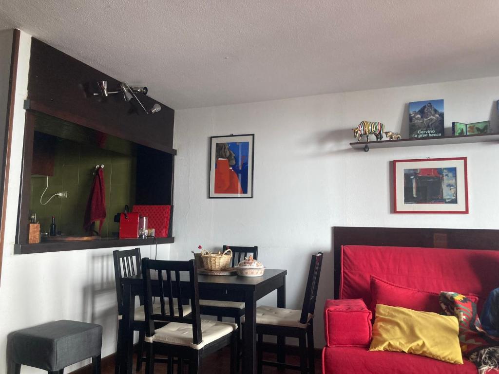 ein Esszimmer mit einem Tisch und einem roten Sofa in der Unterkunft Appartamento + box a Cervinia con vista in Breuil-Cervinia