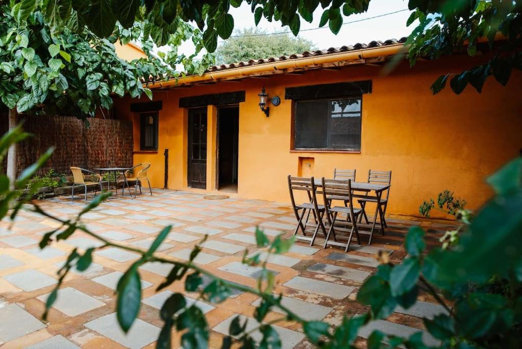 a patio with chairs and a table in front of a house at LAS GLICINIAS casa rural en el campo in Tordera