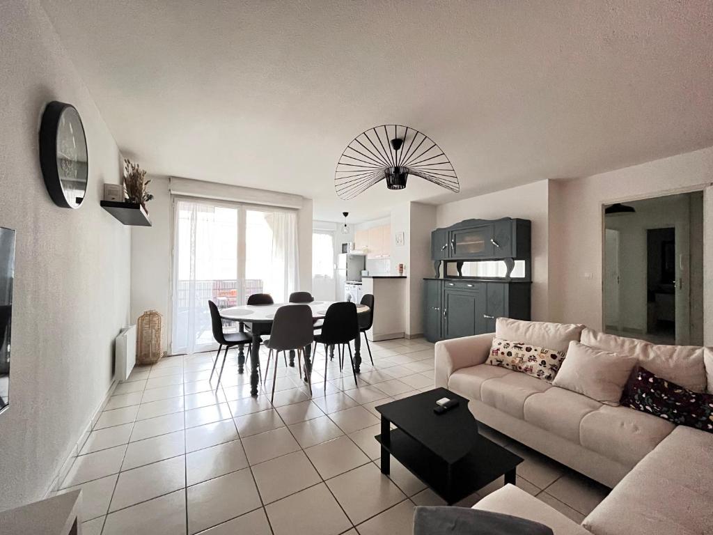 uma sala de estar com um sofá e uma mesa em Le Verrières - Appartement Cozy avec balcon proche de la gare em Clermont-Ferrand