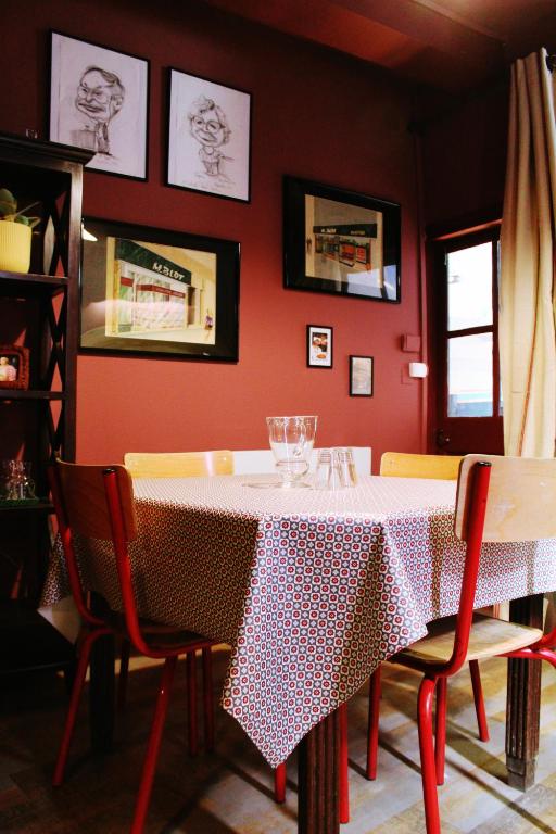 una sala da pranzo con tavolo, sedie e parete rossa di Eau Berges - Chez Mamie a Vicdessos