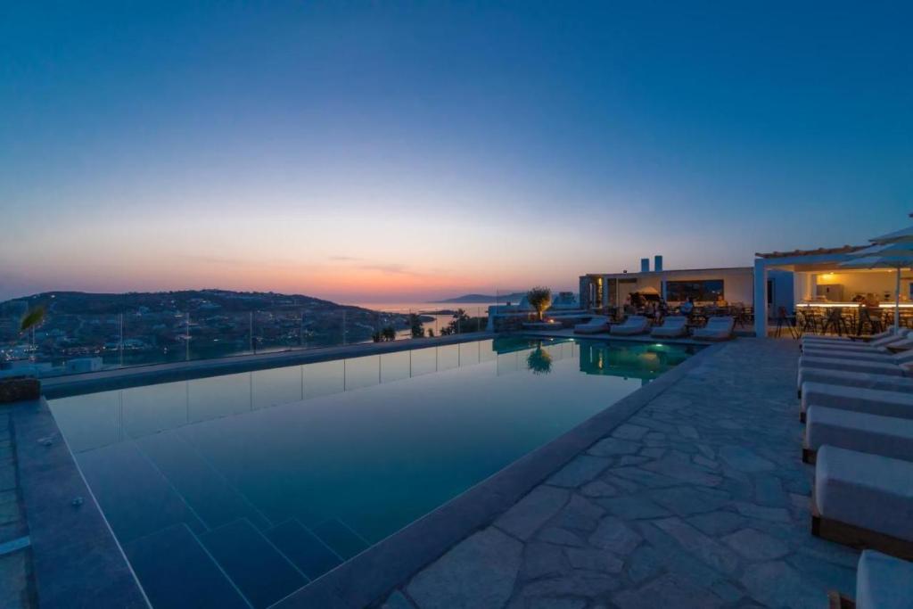 a large swimming pool with a sunset in the background at Sonia in Mikonos