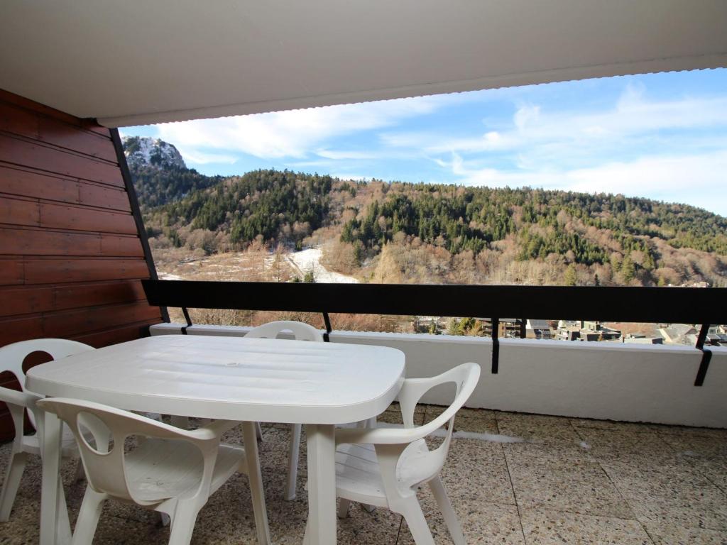 une table blanche et des chaises sur un balcon avec vue dans l'établissement Mont-Dore: Beau T3 avec terrasse, garage et wifi - FR-1-608-178, à Le Mont-Dore