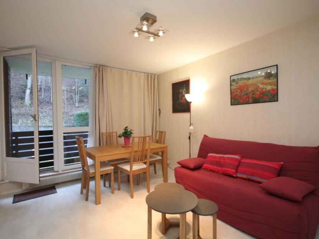 ein Wohnzimmer mit einem roten Sofa und einem Tisch in der Unterkunft Appartement Mont-Dore, 2 pièces, 4 personnes - FR-1-608-189 in Le Mont-Dore