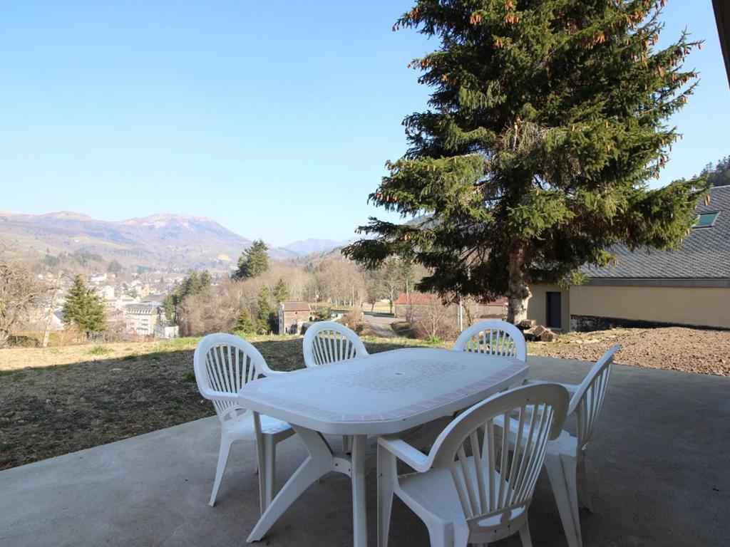 a white table and chairs on a patio with a tree at Maison La Bourboule, 3 pièces, 8 personnes - FR-1-608-203 in La Bourboule