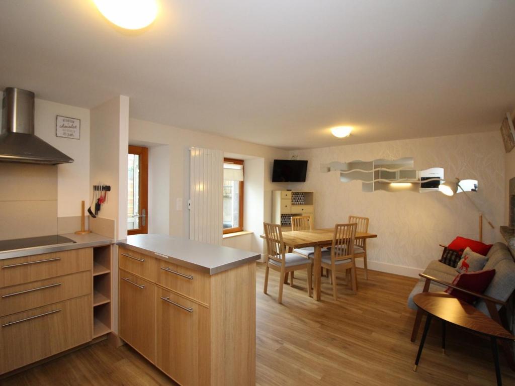une cuisine et un salon avec une table et des chaises dans l'établissement Le Mont-Dore : Appartement 3 pièces avec terrasse et WIFI à 300m des Thermes - FR-1-608-204, à Le Mont-Dore