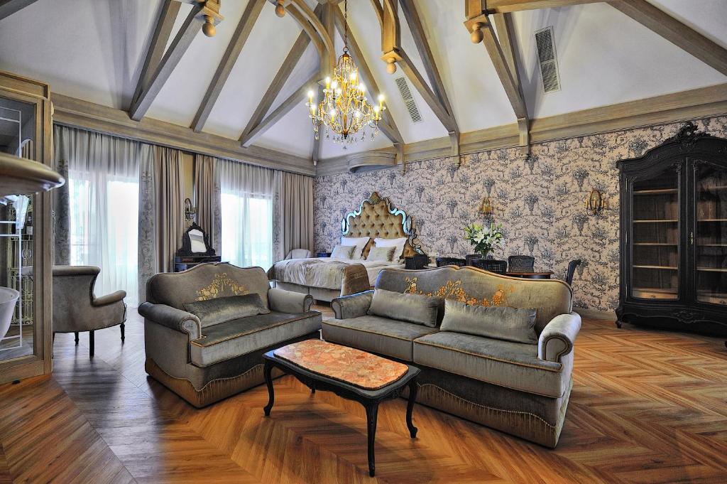 a living room with a bed and a couch and chairs at Złota Łania Wiartel Resort & SPA in Wiartel