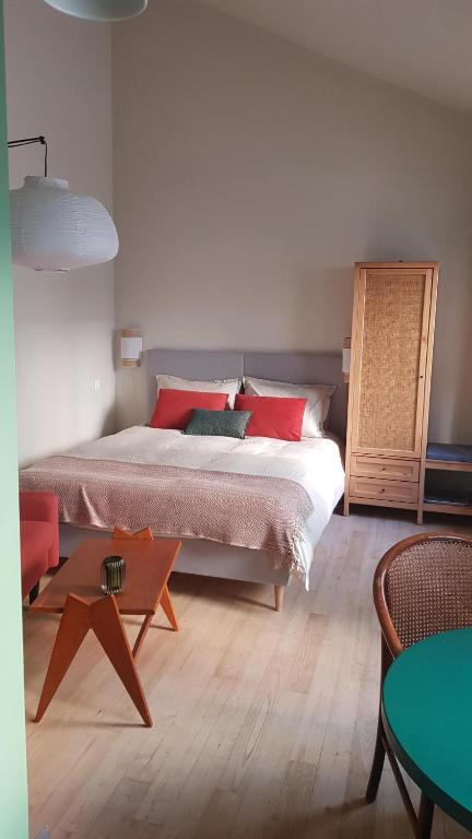 a bedroom with a bed with red pillows and a table at Maisonnette cosy cœur centre avec accueil vélo in Saumur