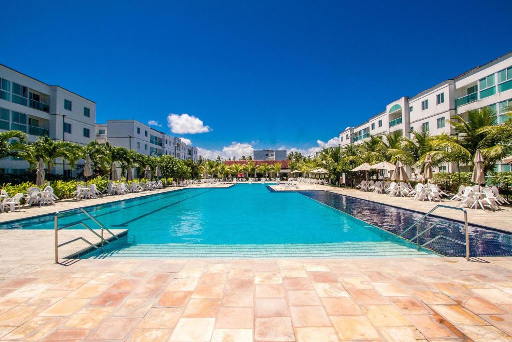 a swimming pool in a resort with chairs and palm trees at Apartamento Frente Piscina Térreo no Palm Village em Porto de Galinhas - Eco11 in Porto De Galinhas