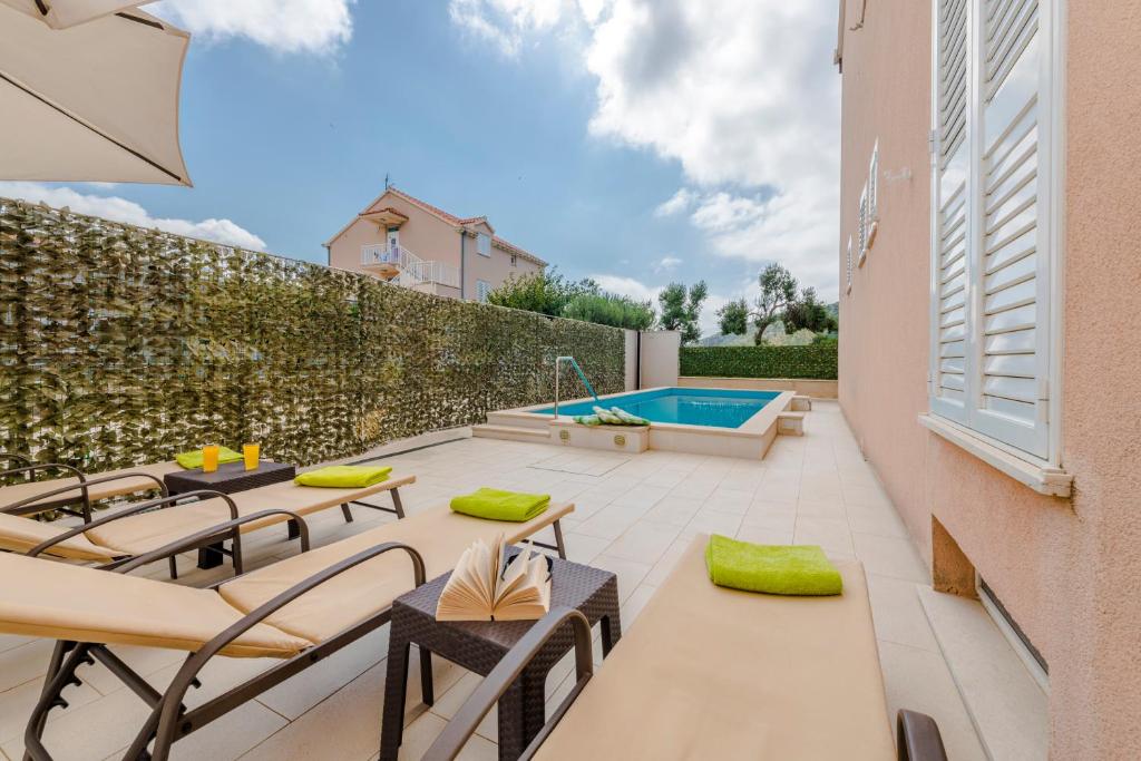 um pátio com mesas e cadeiras e uma piscina em Holiday Home Iva em Mlini