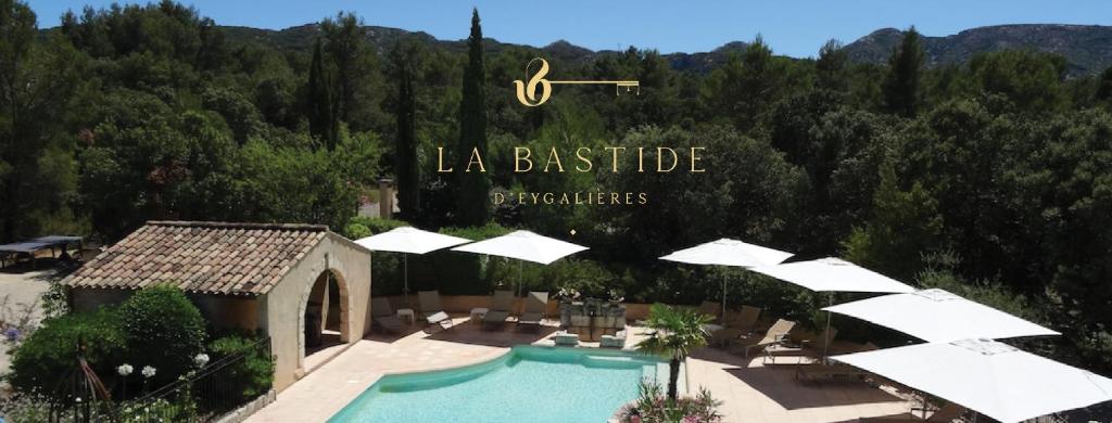 un complexe avec une piscine bordée de parasols dans l'établissement Hotel La Bastide d'Eygalières, à Eygalières