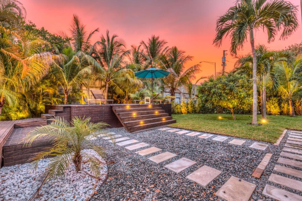 a garden with a bench and an umbrella at Quiet and secluded 4 bedroom home! in Fort Lauderdale