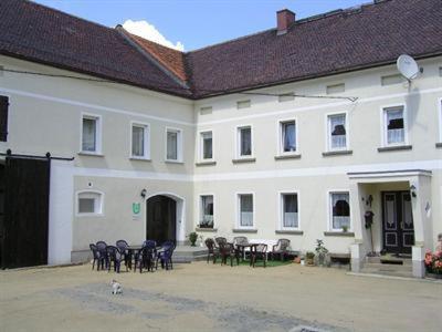 ein weißes Gebäude mit Stühlen und einem Tisch davor in der Unterkunft Pension Rotsteinblick in Sohland am Rotstein