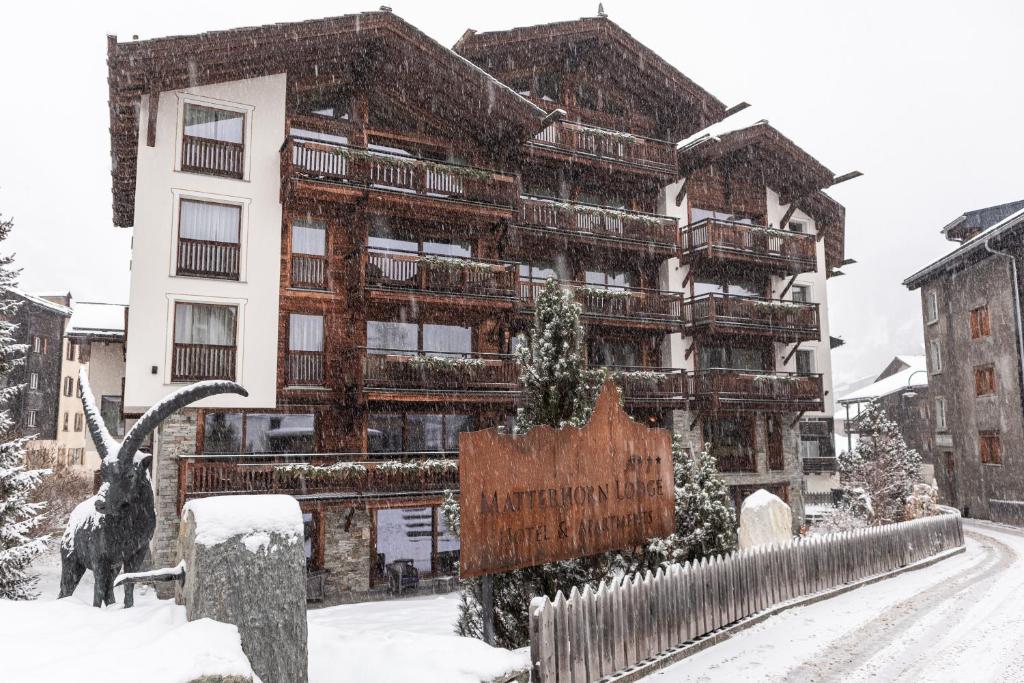 a building in the snow with a goat in front of it at Matterhorn Lodge Boutique Hotel & Apartments in Zermatt