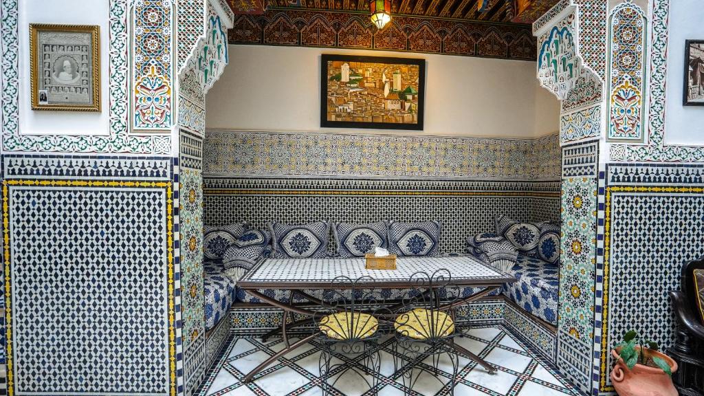 Habitación con mesa y azulejos azules y blancos. en Riad Green House en Fez
