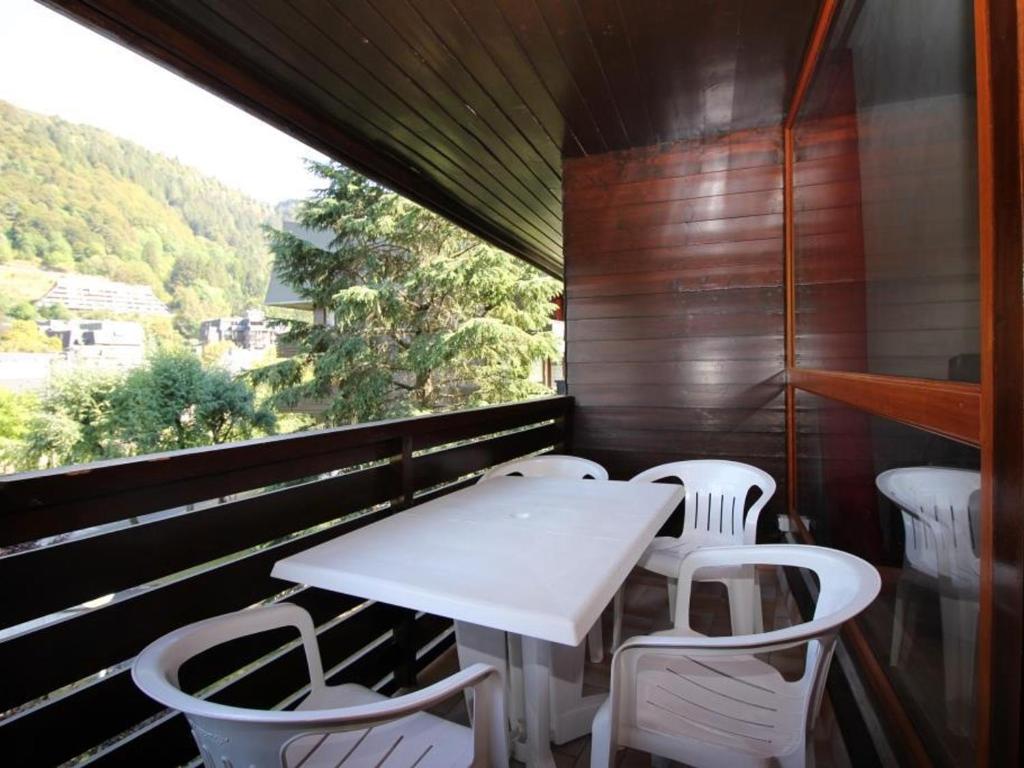 une table et des chaises sur un balcon avec une fenêtre dans l'établissement Beau Duplex T3 avec Balcon, Wifi et Parking à 300m du Centre - FR-1-608-16, à Le Mont-Dore