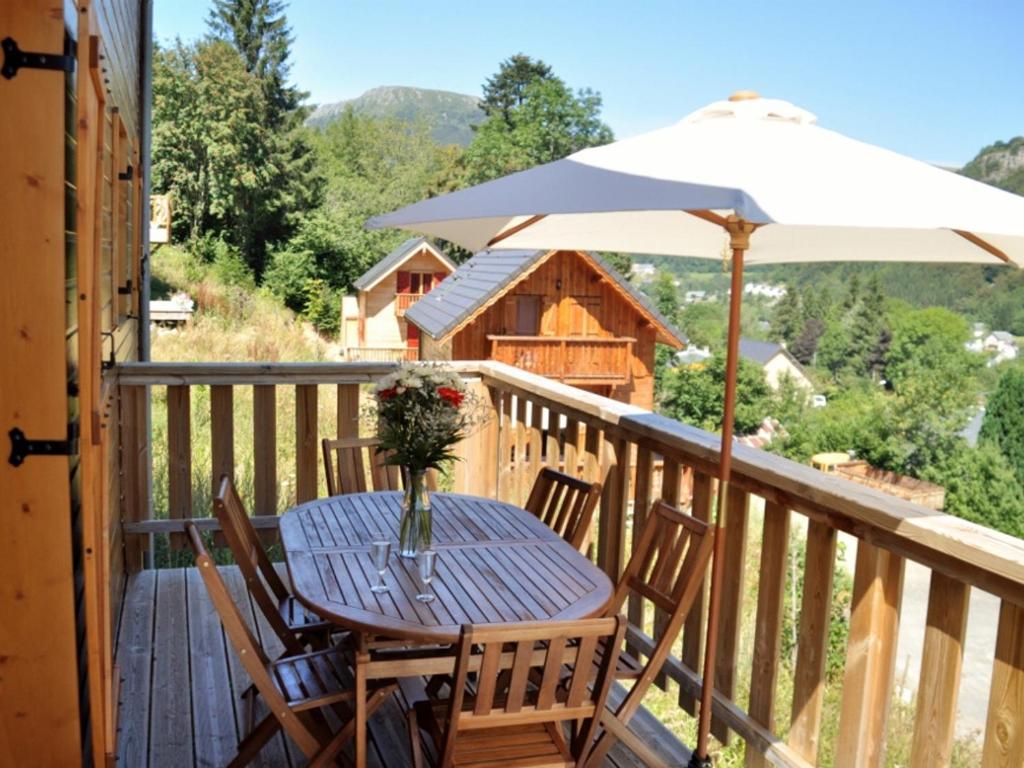 a table and chairs on a deck with an umbrella at Chalet Mont-Dore, 5 pièces, 8 personnes - FR-1-608-31 in Le Mont-Dore