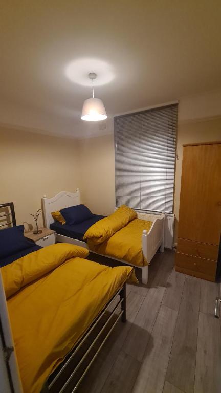 pokój z 2 łóżkami z żółtą pościelą w obiekcie Entire 2 Bedroom Home/Flat In London, Central Line w Londynie