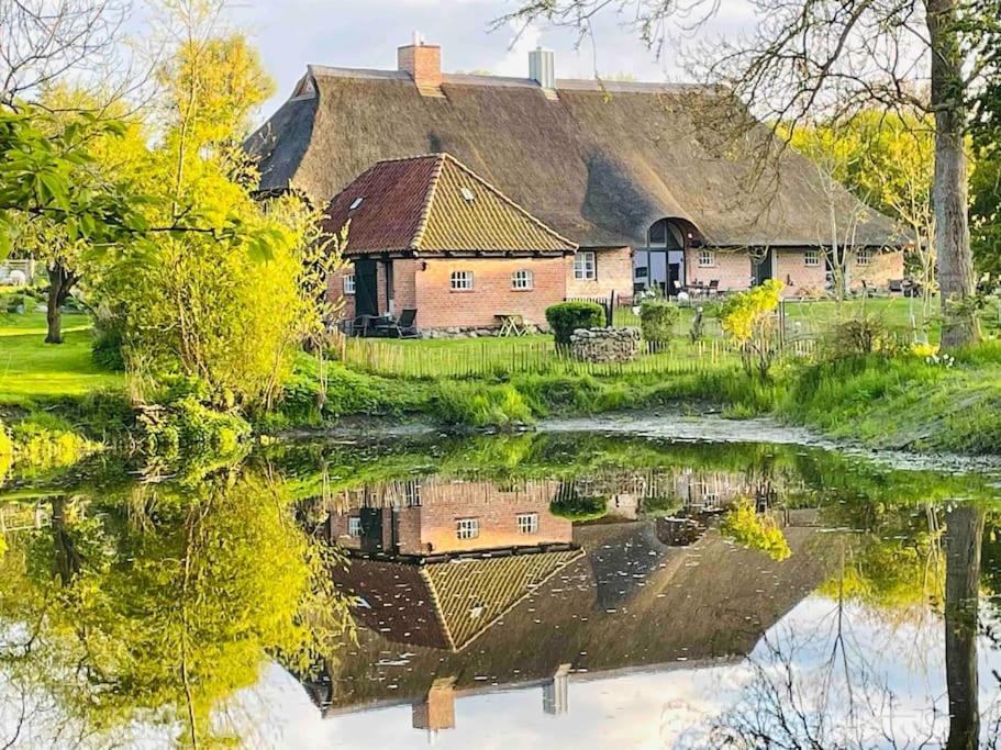 an old house with a reflection in a river at Ferienwohnung mit Luxusbad, Terrasse Ostseenähe in Gremersdorf