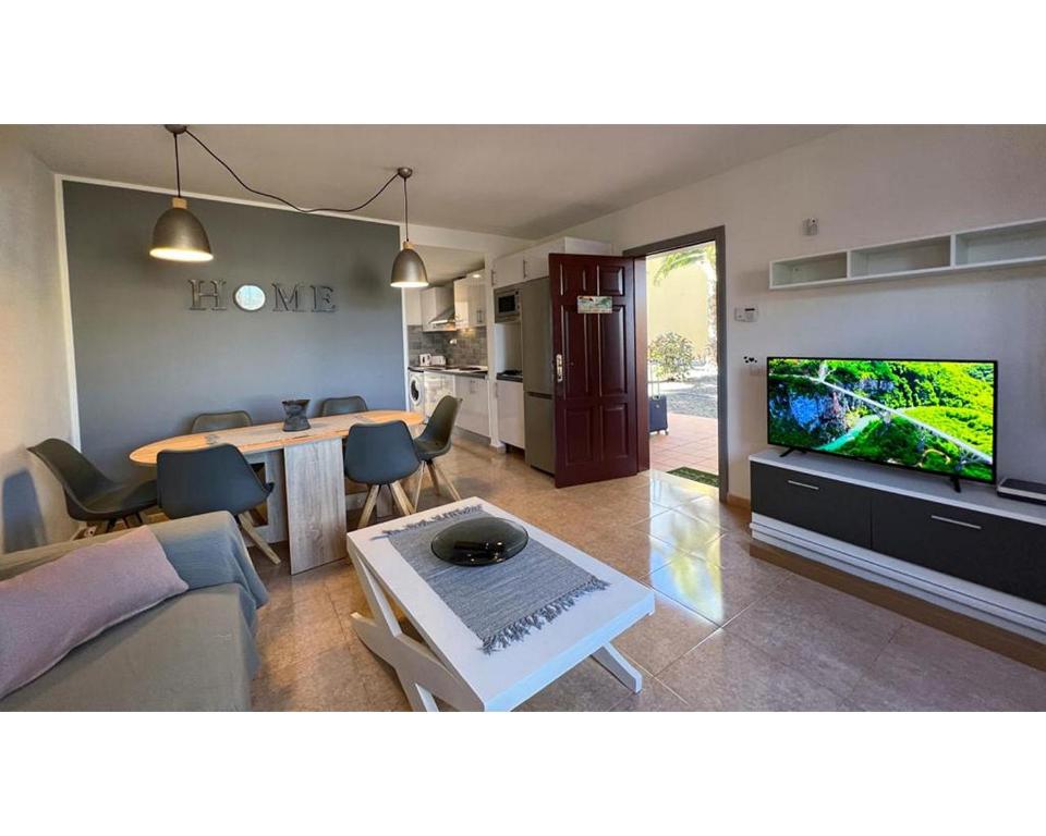 a living room with a couch and a tv and a table at Casa Sofia in Corralejo