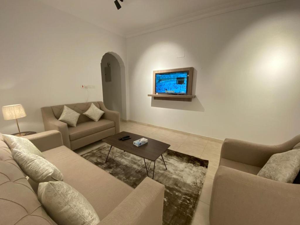 a living room with a couch and a tv on the wall at نايتس للوحدات المفروشة in Tabuk