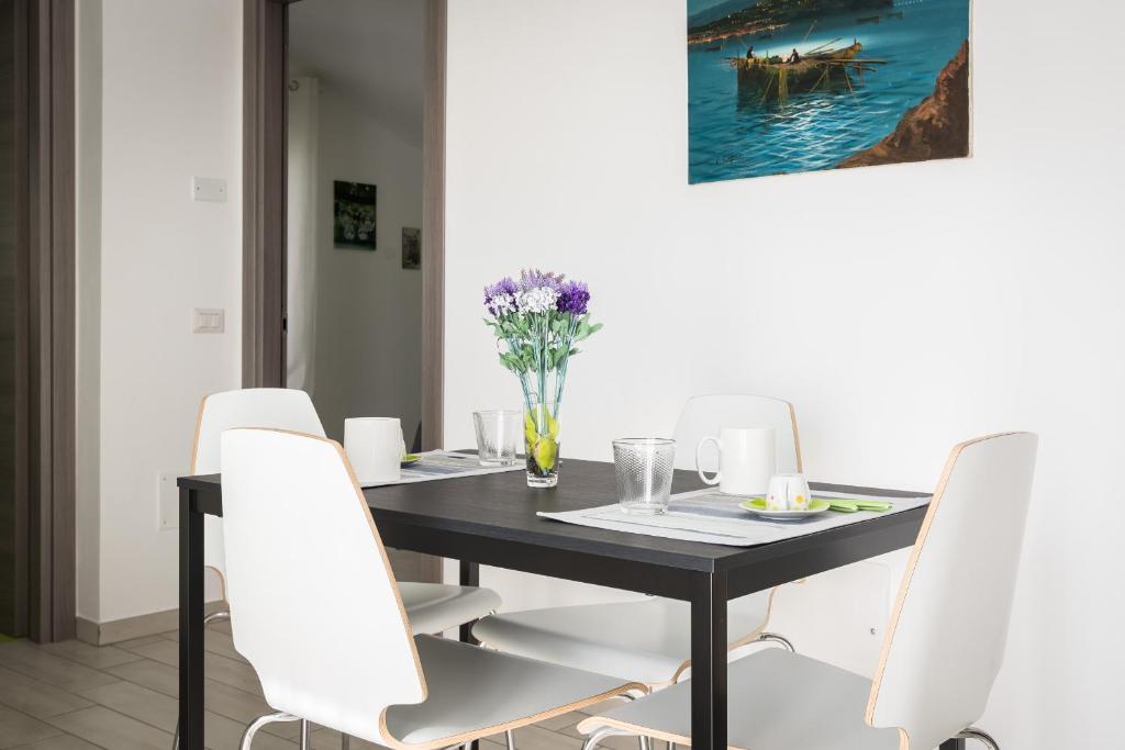 una sala da pranzo con tavolo nero e sedie bianche di Residence Rossomelograno ad Agropoli