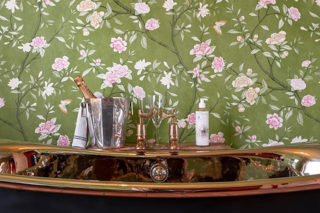 a bathroom with a sink with flowers on a wall at Rumple Cottage in Wingfield