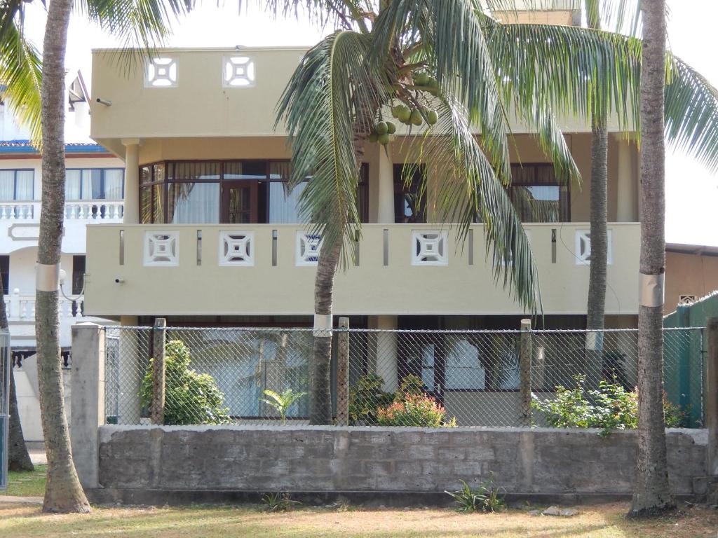 un bâtiment avec des palmiers en face de celui-ci dans l'établissement Janishi Residencies, à Negombo