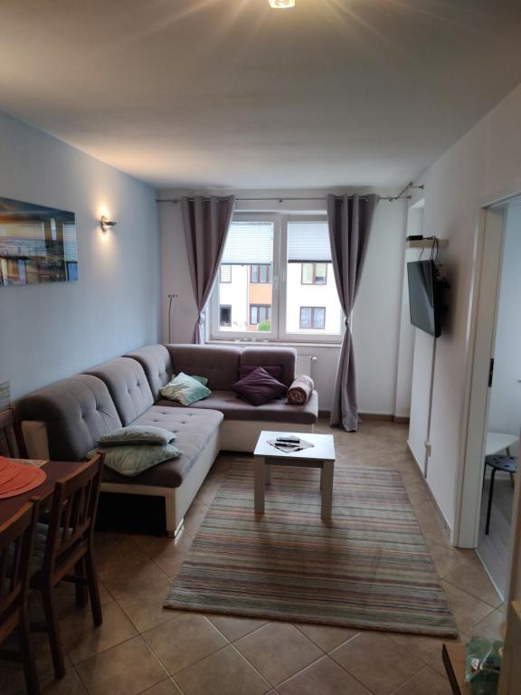 a living room with a couch and a table at Apartament Perełka Zielone Tarasy Kołobrzeg in Kołobrzeg