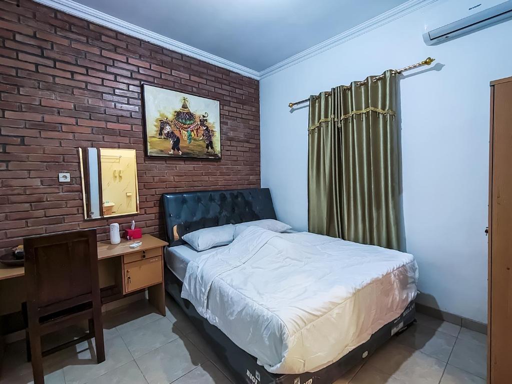 een slaapkamer met een bed, een bureau en een bakstenen muur bij Homestay dwi prasetyo in Kembanglimus