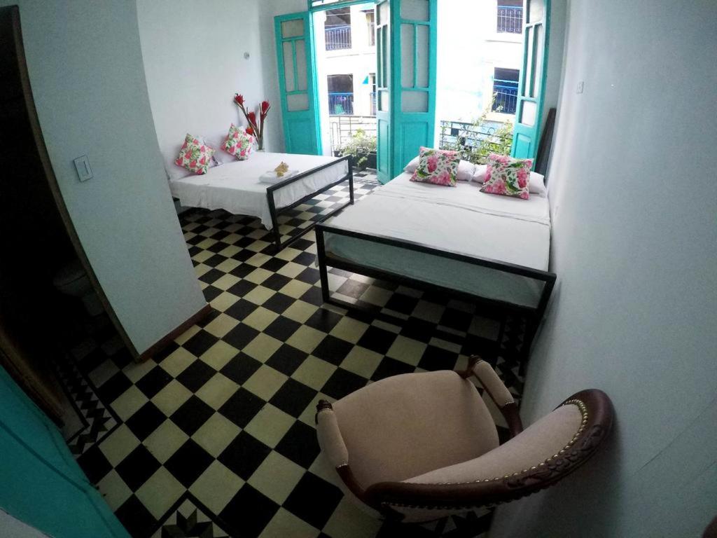 Habitación con 2 camas y silla en Casa La Bella Samaria Boutique, en Santa Marta