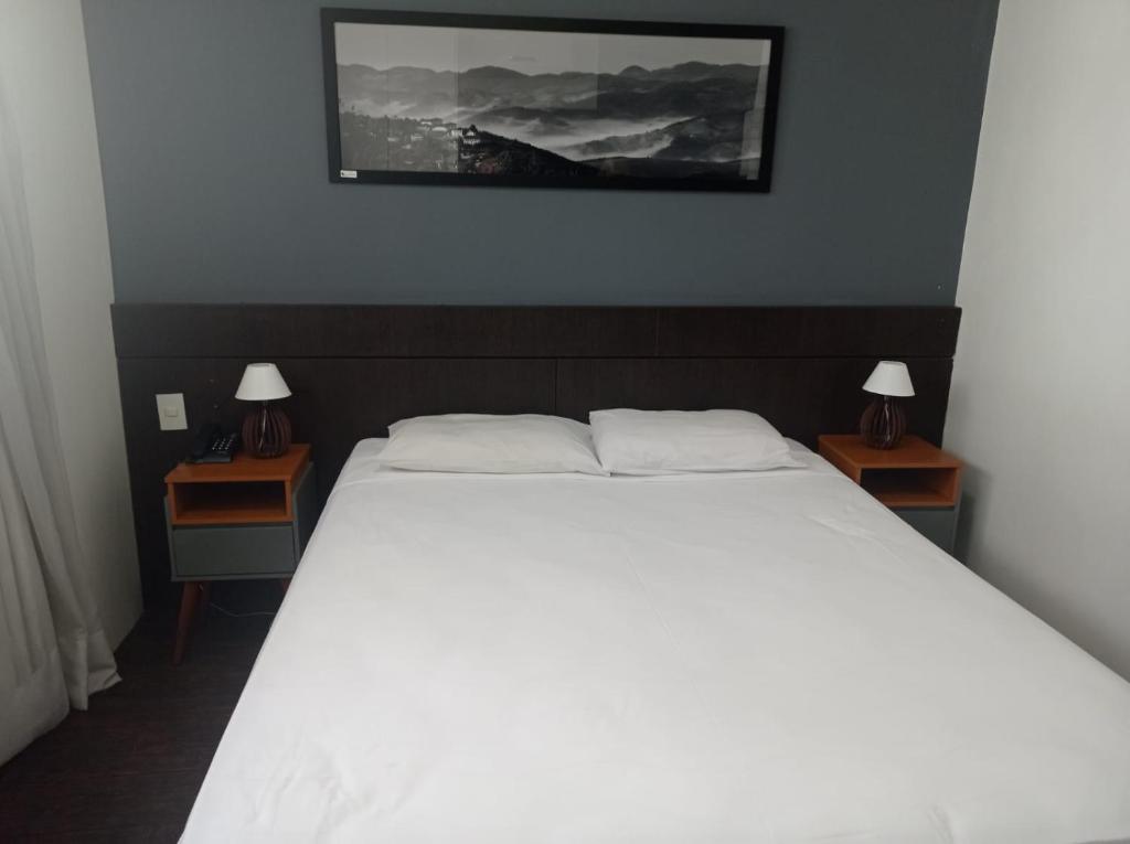 een slaapkamer met een groot wit bed en 2 nachtkastjes bij Apartamento San Diego Pampulha Propriedade Particular in Belo Horizonte