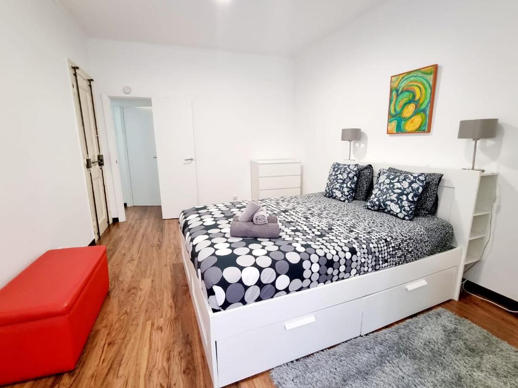 - une chambre blanche avec un lit et un pouf rouge dans l'établissement Anjos Apartment - Ilha do Príncipe, à Lisbonne